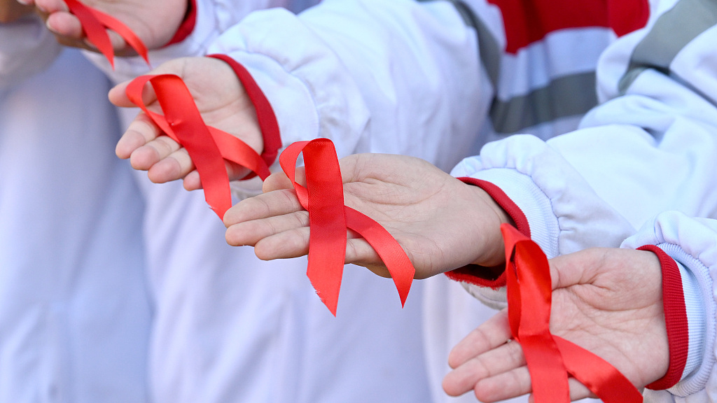 Students show off the red ribbons they made, the universal symbol of awareness and support for people living with HIV, in Handan City, central China's Hebei Province, December 1, 2023. /CFP