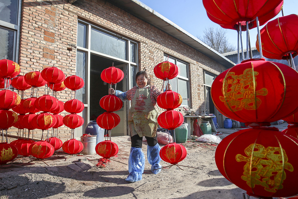 A worker in Yangzhao Village, Yuncheng City, Shanxi Province, carries red lanterns on December 1, 2023. /CFP