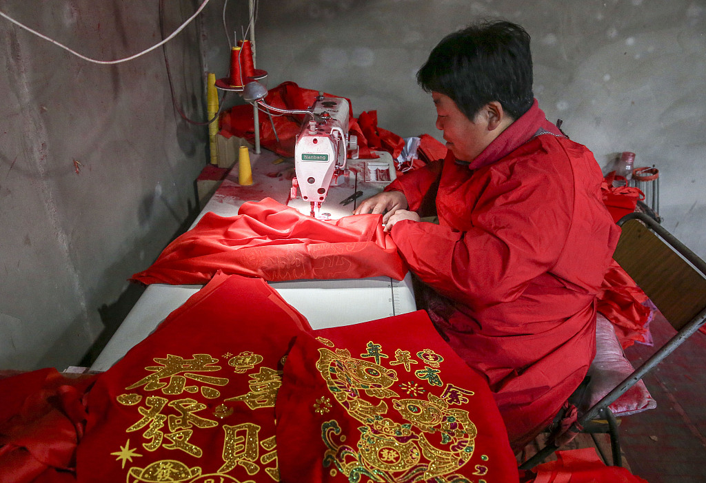 A worker in Yangzhao Village, Yuncheng City, Shanxi Province, sews auspicious Chinese words onto cloth on December 1, 2023. /CFP