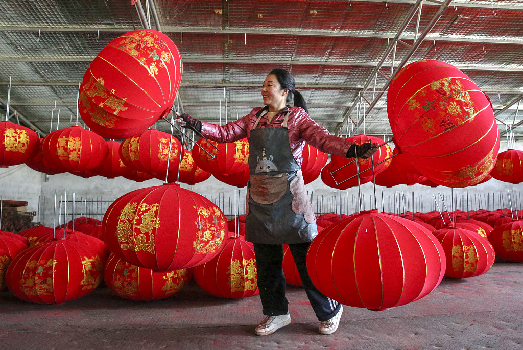 A worker in Yangzhao Village, Yuncheng City, Shanxi Province, holds red lanterns on December 1, 2023. /CFP