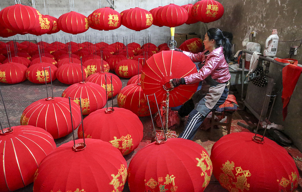A worker in Yangzhao Village, Yuncheng City, Shanxi Province, paints gold lines onto a red lantern on December 1, 2023. /CFP