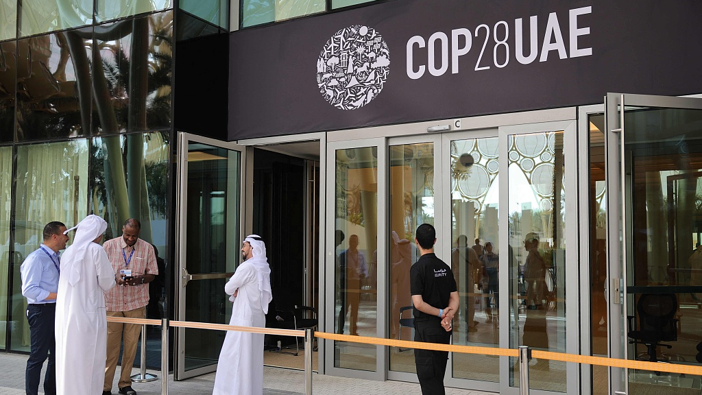 People wait outside a building adorned with a COP28 logo ahead of the United Nations climate summit in Dubai, the UAE, November 28, 2023. /VCG