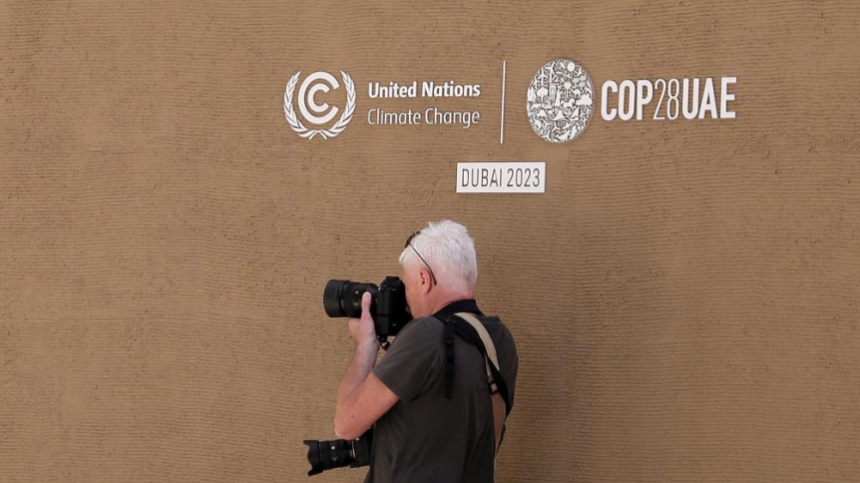 A photographer takes photos underneath a logo of COP28 in Dubai, the United Arab Emirates, November 29, 2023. /Xinhua