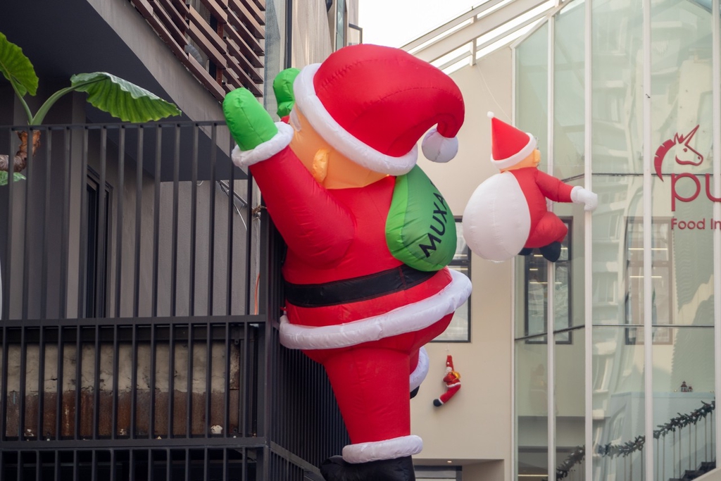A photo taken on December 5, 2023 shows Santa Claus decorations placed on the exterior of buildings in Haungpu District, Shanghai, resembling Saint Nick climbing in to deliver presents. /IC