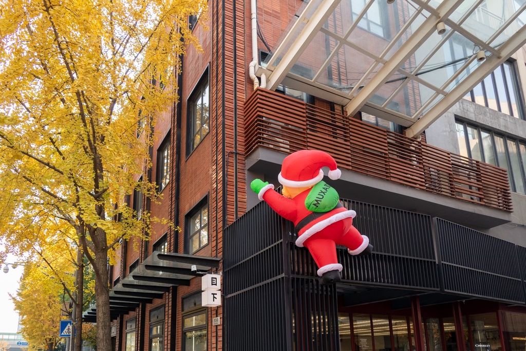 A photo taken on December 5, 2023 shows a Santa Claus decoration placed on the exterior of a building in Haungpu District, Shanghai, resembling Saint Nick climbing in to deliver presents. /IC