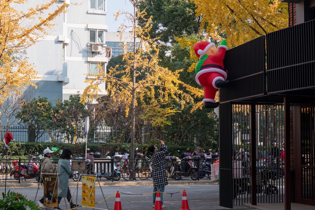 A photo taken on December 5, 2023 shows residents stopping to take pictures of a Santa Claus decoration placed on the exterior of a building in Haungpu District, Shanghai. /IC