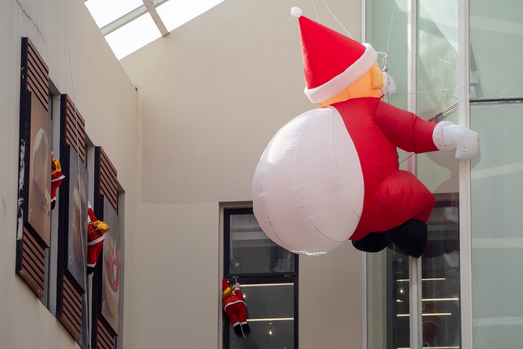 A photo taken on December 5, 2023 shows a Santa Claus decoration placed on the exterior of a building in Haungpu District, Shanghai, resembling Saint Nick climbing in to deliver presents. /IC