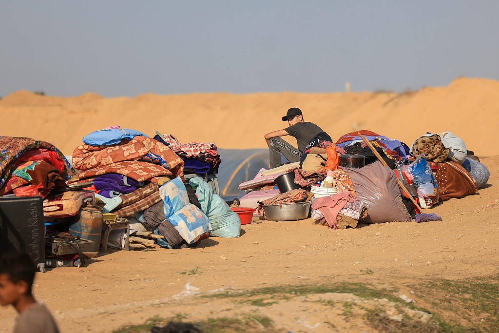 A displaced Palestinian sits with his belongings at a camp in Rafah on the southern Gaza Strip after fleeing Khan Younis, December 4, 2023. /CFP
