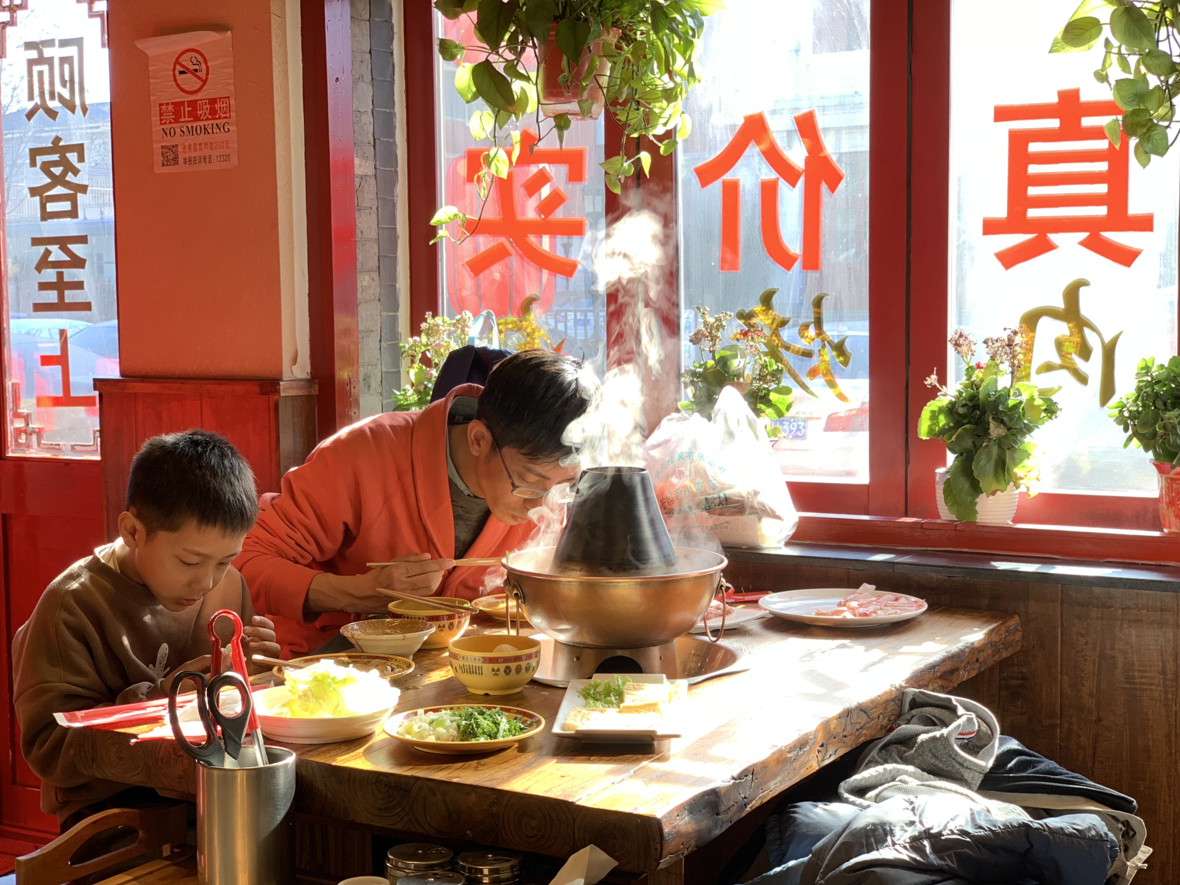 A file photo shows a father and son enjoying a hot pot at a restaurant in Beijing. /CGTN