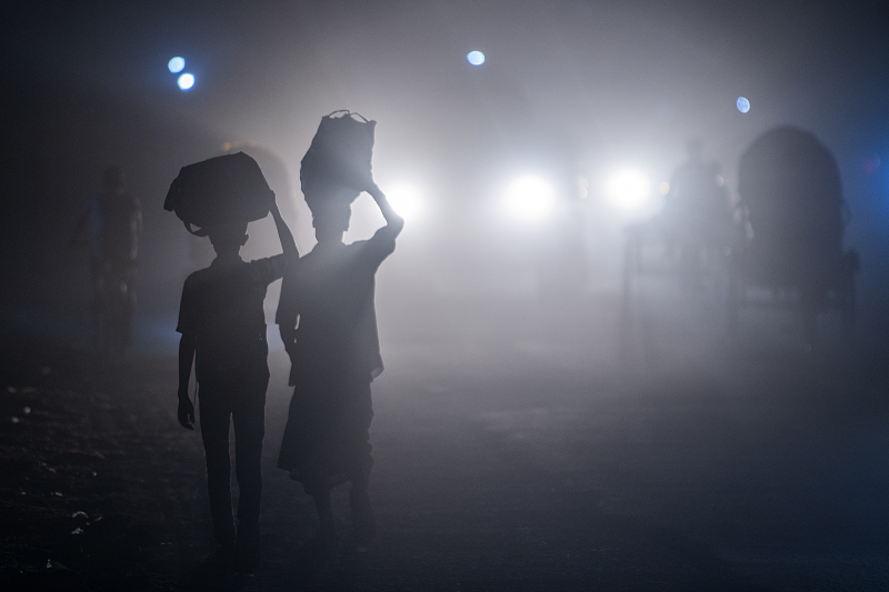 People are moving along a dusty road in Dhaka, Bangladesh, December 5, 2023. /CFP