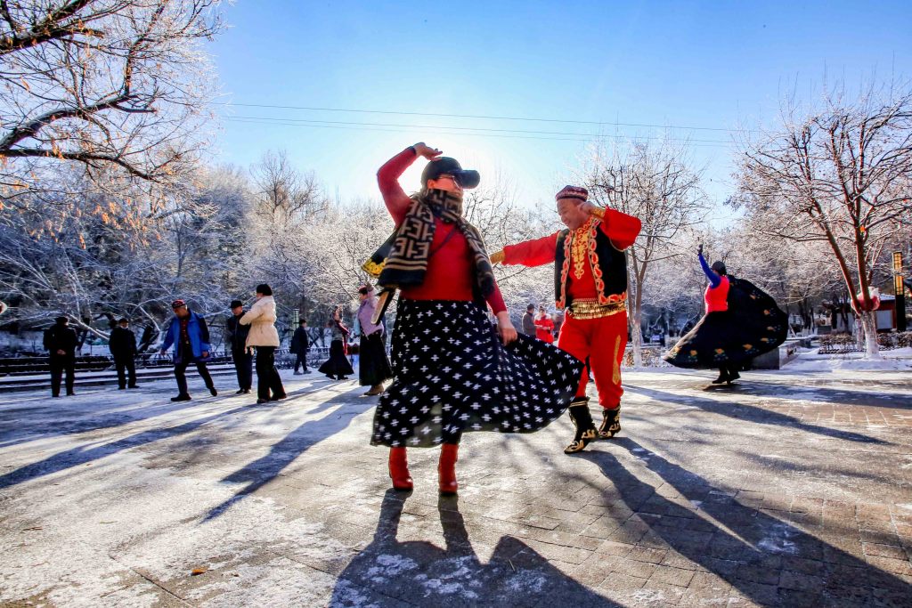 A photo shows residents dancing in the sunlight amid rime-covered trees in the Shuimogou Scenic Area of Urumqi, Xinjiang on December 5, 2023. /CFP