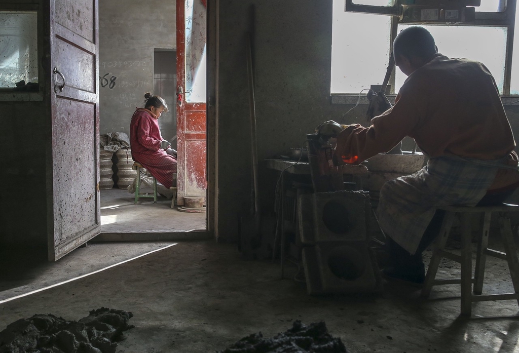 Craftsman Huang Tiande and his wife work on hot pots in Jishan County of Yuncheng, Shanxi on December 6, 2023. /IC