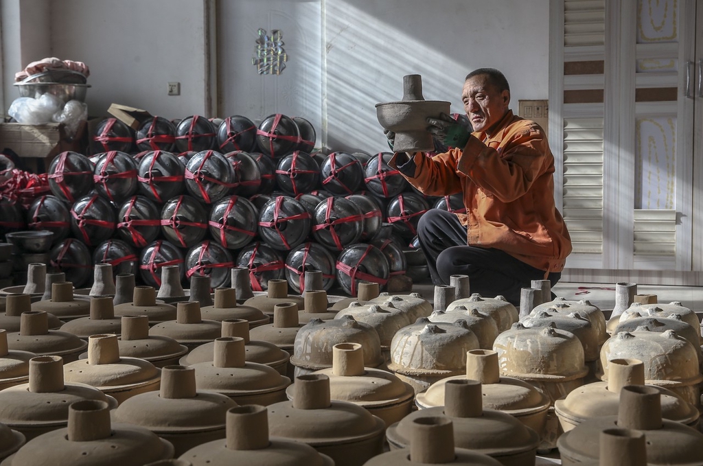 Craftsman Huang Tiande examines one of his hot pots in Jishan County of Yuncheng, Shanxi on December 6, 2023. /IC