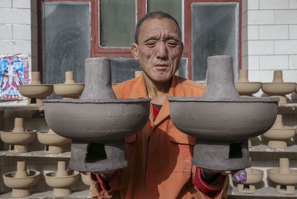 Craftsman Huang Tiande displays his hot pots in Jishan County of Yuncheng, Shanxi on December 6, 2023. /IC