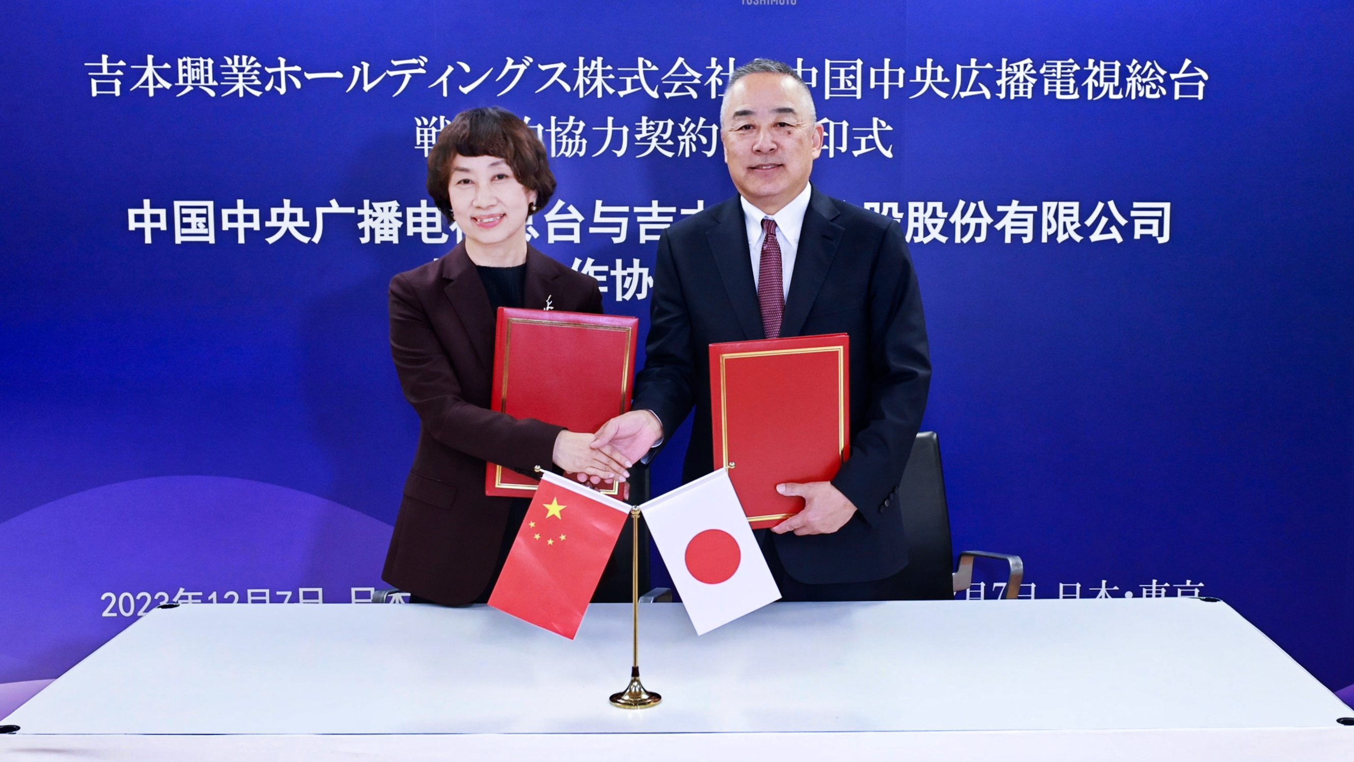 Xing Bo (L), vice president of CMG, shakes hands with Yoshimoto Kogyo President Akihiko Okamoto at a signing ceremony in Tokyo, Japan, December 7, 2023. /CMG