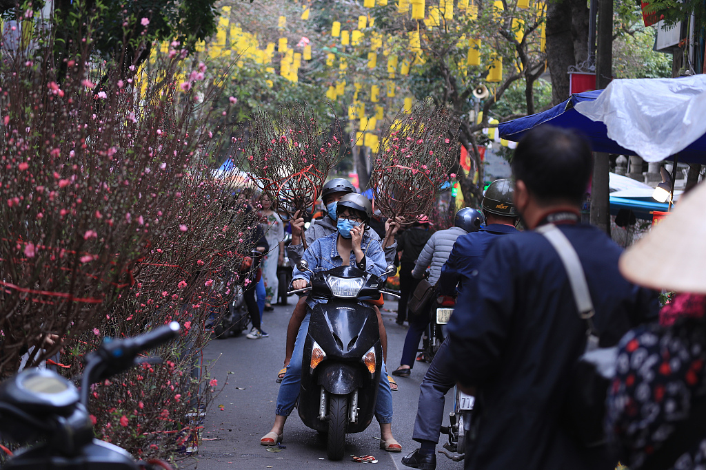 People shop for peach blossoms for Tet at a market in Hanoi, Vietnam on January 28, 2022. /CFP
