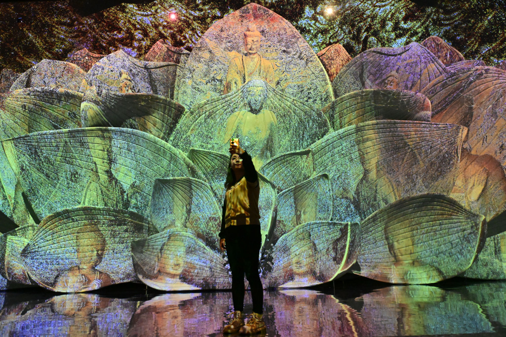A visitor takes a selfie while visiting an immersive exhibition featuring Chinese grotto art at the National Museum of China in Beijing on December 9, 2023. /CFP