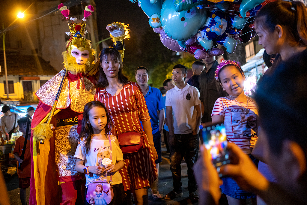 Visitors pose for photos with a man costumed as Sun Wukong, or the Monkey King from Chinese mythology, as part of local Mid-Autumn Festival celebrations in Hanoi, Vietnam, on September 26, 2020. /CFP