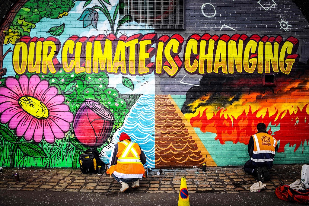 Artistas callejeros británicos pintan una pared para llamar la atención sobre el cambio climático.  /PPC