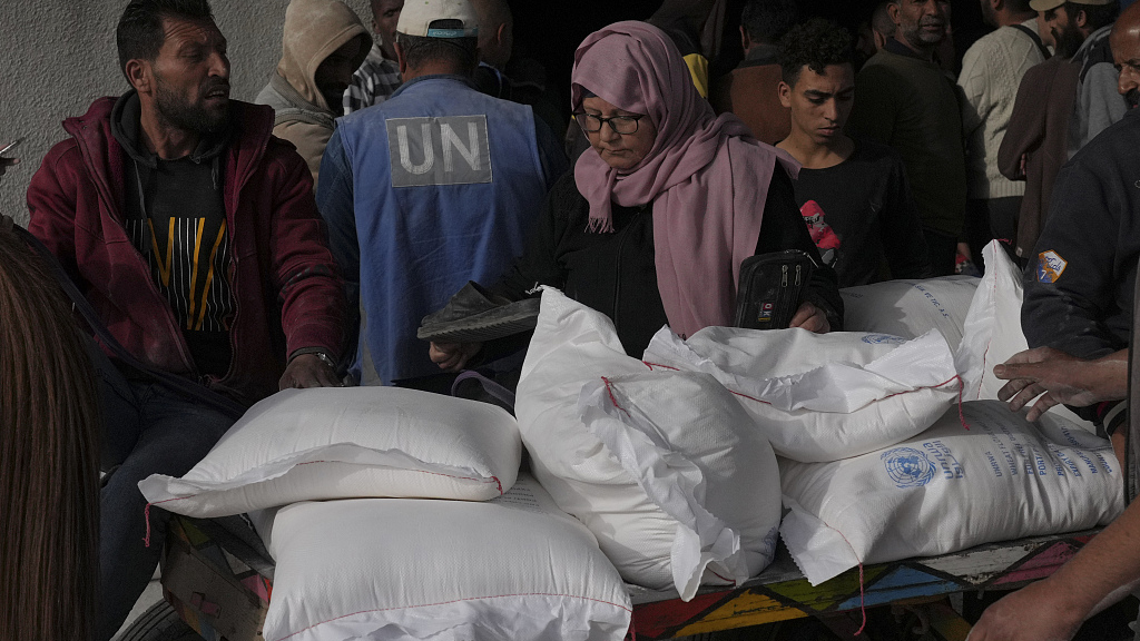 Palestinians take wheat from a UN distribution center in the Bureij refugee camp in Gaza, December 10, 2023. /CFP