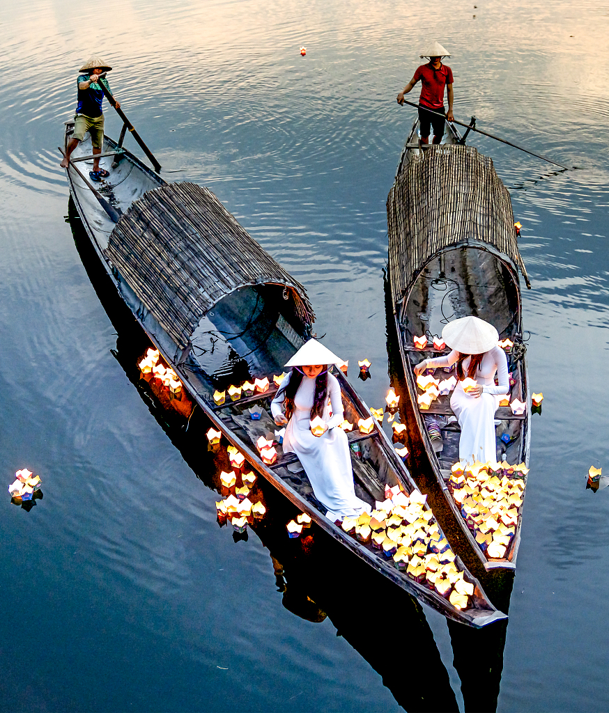 A photo taken on June 30, 2022 shows Vietnamese women placing flower lanterns on the Nhu Y River in Hue, Vietnam. /CFP