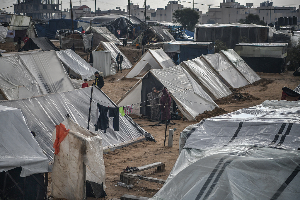 Palestinian families take refuge in makeshift tents they have built around the storage as they struggle with cold weather in Rafah, Gaza, December 13, 2023. /CFP