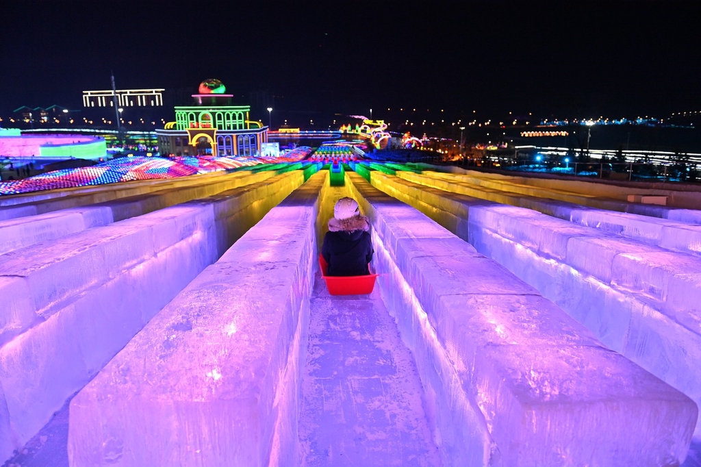 A photo shows a visitor sliding down a lane of the ultra-long ice slide at this year's Changchun Ice and Snow New World in Changchun, Jilin Province on December 12, 2023. /IC