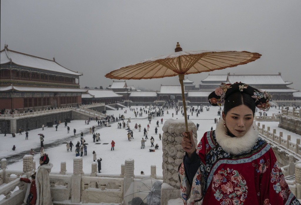 A woman dressed in traditional attire holds up a parasol at the Forbidden City in Beijing on December 13, 2023. /CFP
