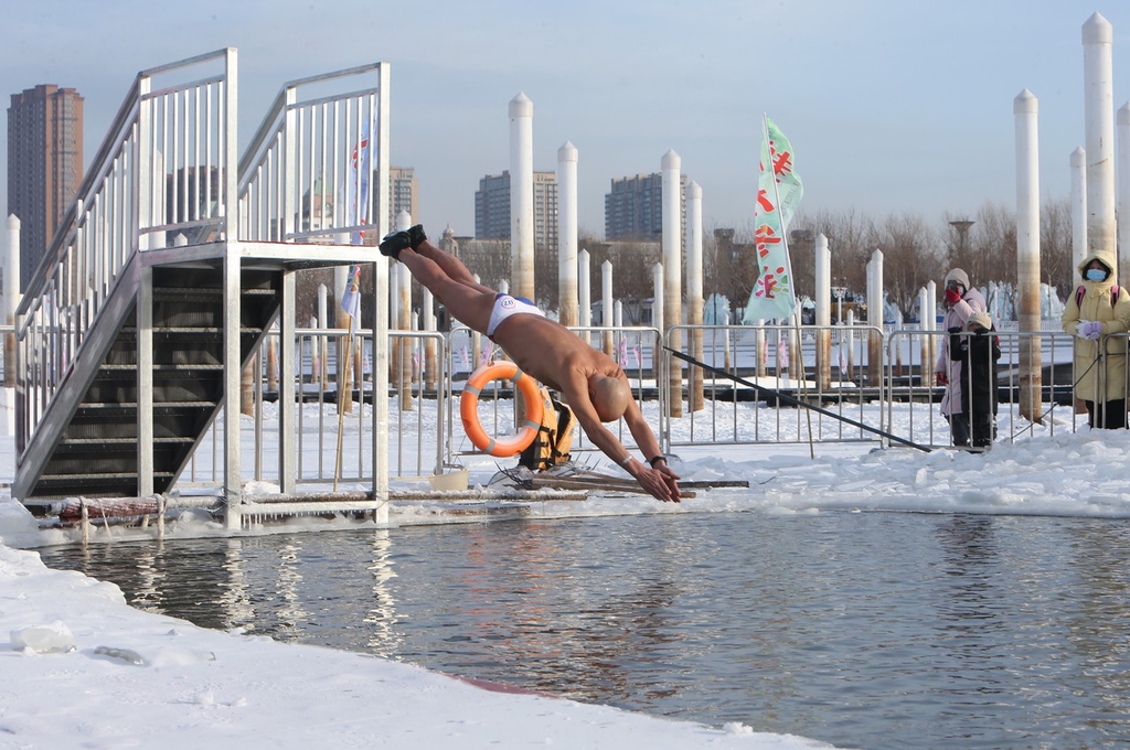 A winter swimmer leaps into the cold waters of Waitan Xueren Wharf in Harbin, Heilongjiang Province on December 12, 2023. /IC