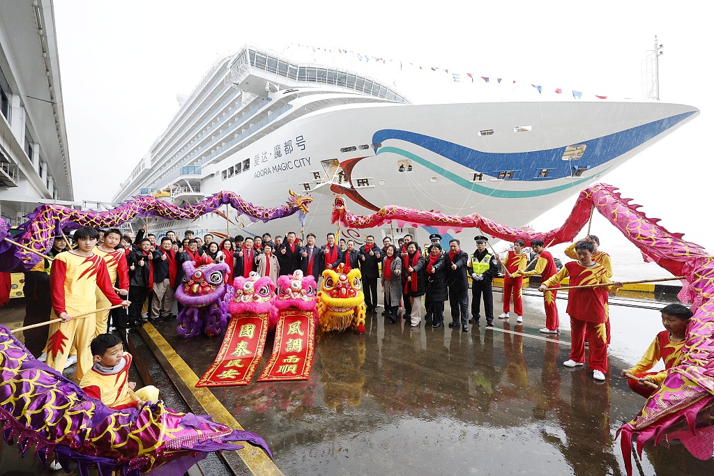 Guests pose for a photo after the Adora Magic City, China's first domestically built large cruise ship, arrives at the Shanghai Wusongkou International Cruise Terminal on December 15, 2023. /CFP