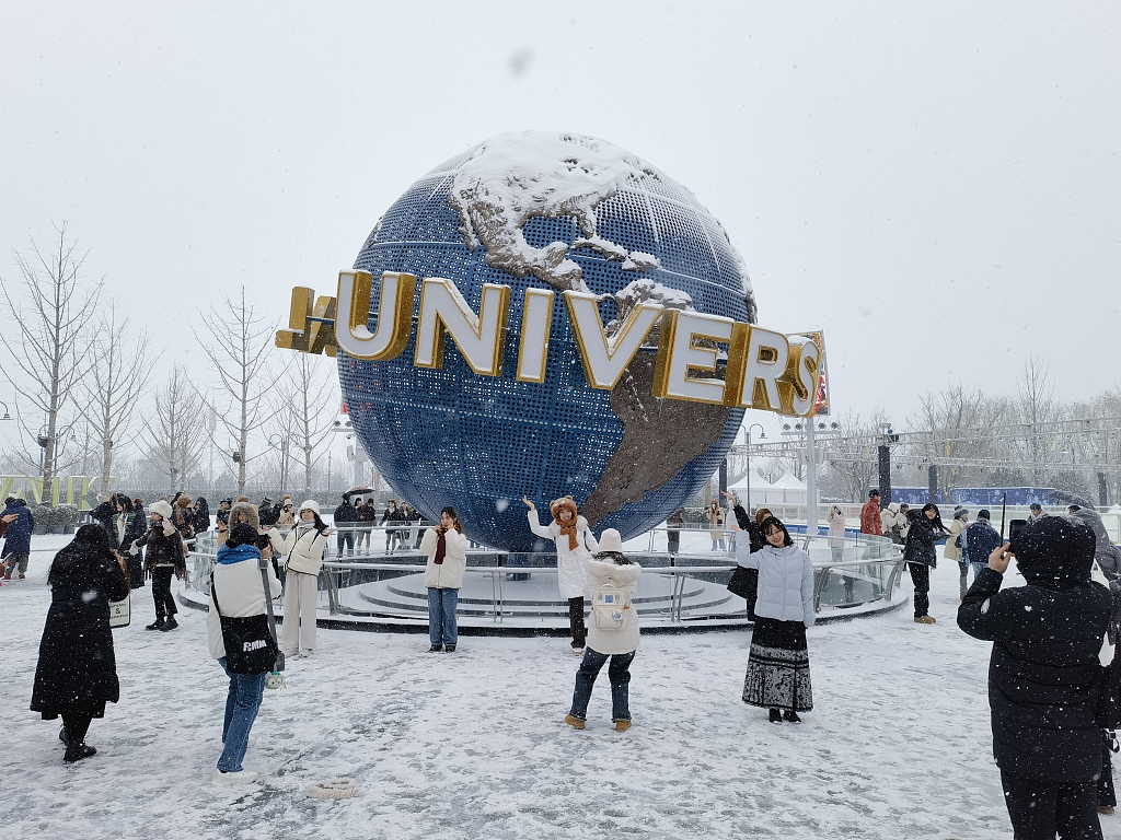 Visitors to the Universal Beijing Resort take photos in the snow on December 14, 2023. /CFP