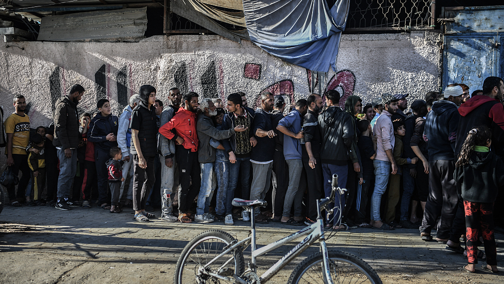 Palestinian families wait in line to receive food distributed by volunteers in Rafah, Gaza, December 16, 2023. /CFP