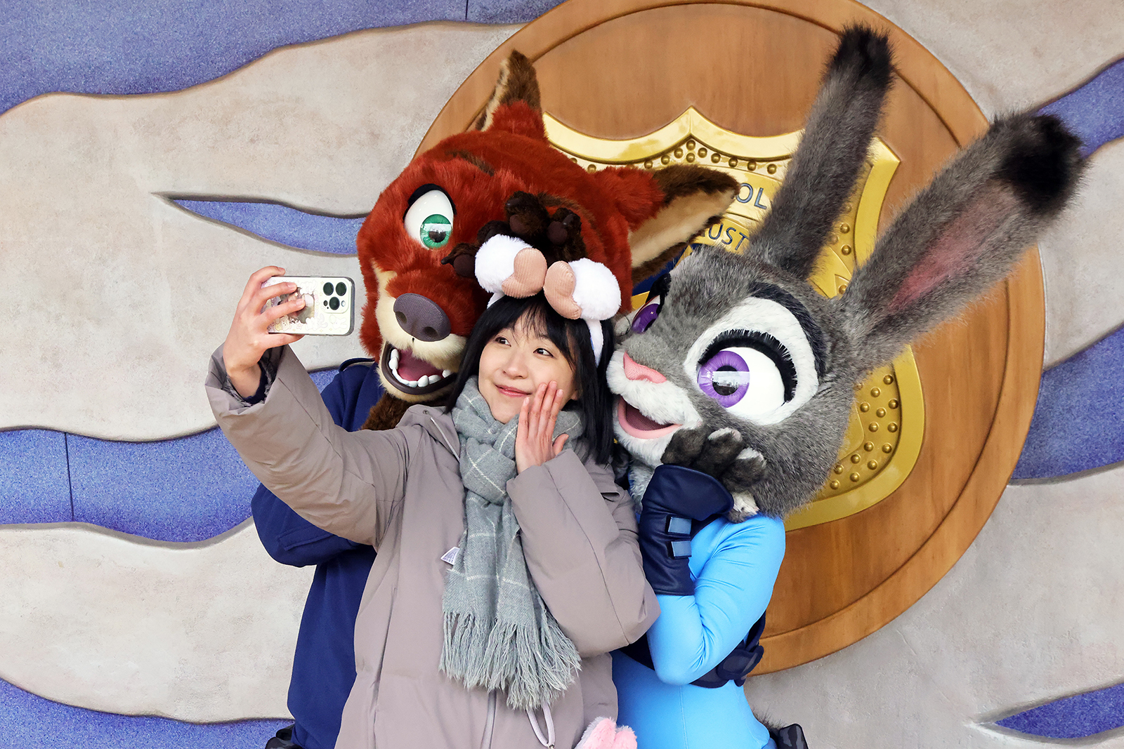 A visitor takes a selfie with the rabbit character Judy Hopps and fox character Nick Wilde, the two central characters in the animated film 