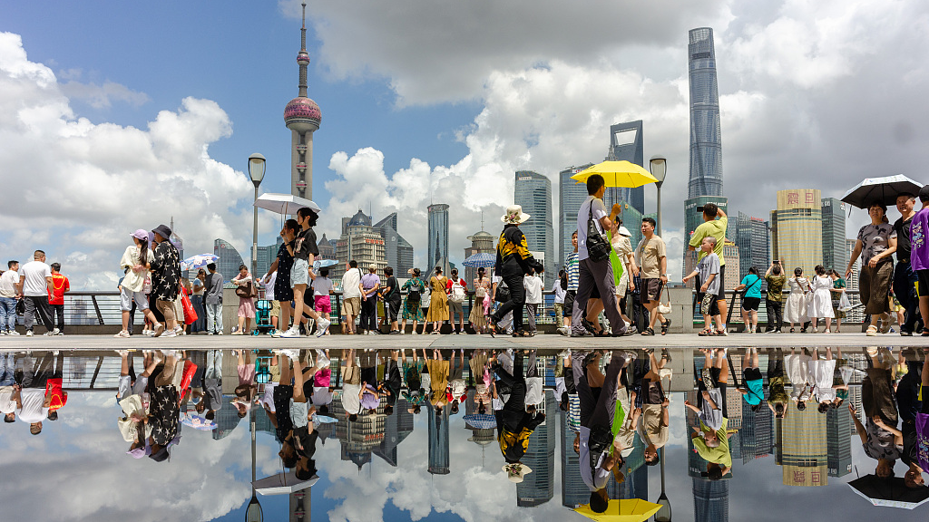Tourists walk on the Bund as their reflections and those of nearby skyscrapers appear in the water, in Shanghai, east China, July 17, 2023. /CFP