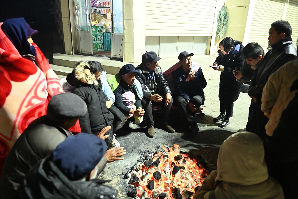 Residents keep warm by the fire, December 19, 2023. A 6.2-magnitude earthquake shook the county midnight December 18, 2023. /Gansu Forest Fire Brigade