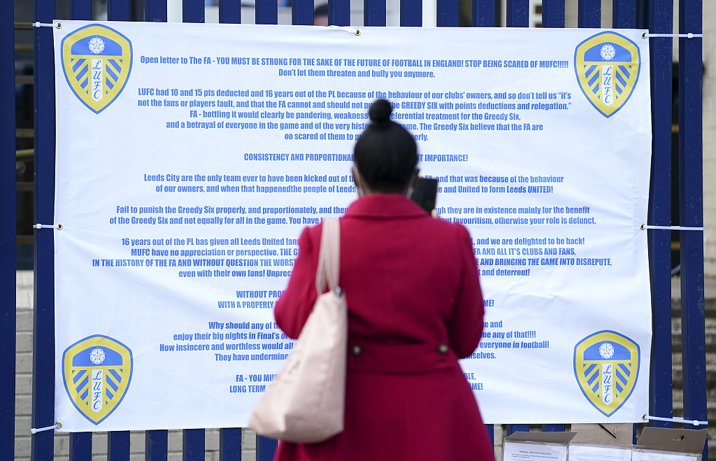 A woman reads a banner issued by the Leeds United Football Club criticizing the English Football Association and the English teams involved in the European Super League ahead of a Premier League match in Leeds, England, April 25, 2021. /CFP