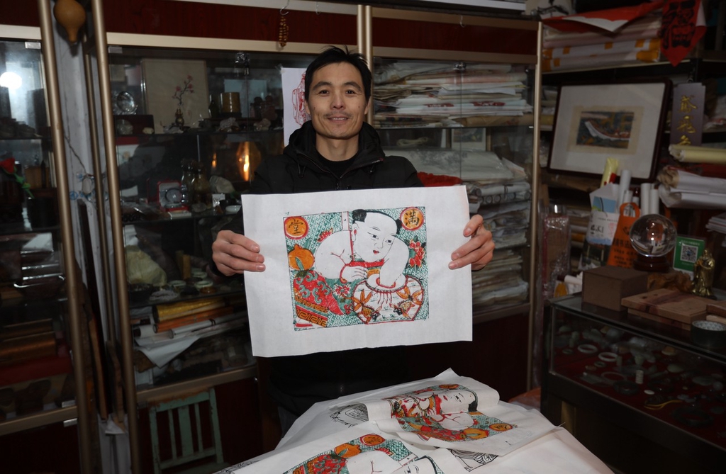 A photo shows craftsman Li Xiangduo holding up one of his Chinese New Year painting creations in Rizhao, Shandong on December 20, 2023. /IC