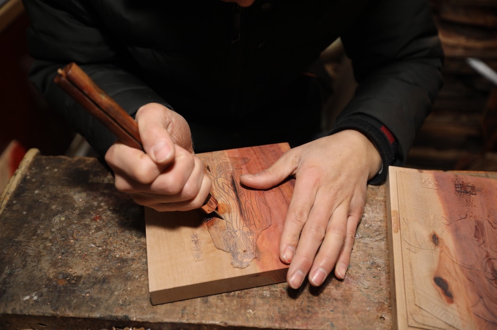 A photo shows craftsman Li Xiangduo chiseling an image onto a woodblock at a studio in Rizhao, Shandong on December 20, 2023. /IC