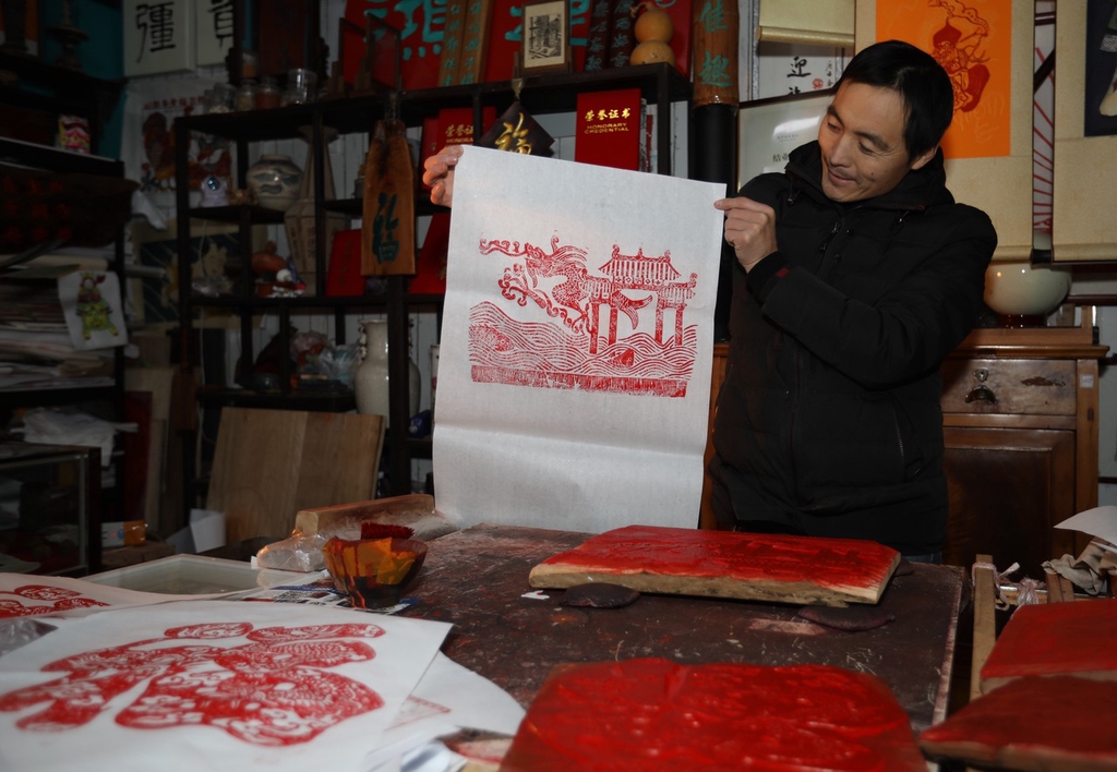 A photo shows craftsman Li Xiangduo holding up one of his Chinese New Year painting creations at a studio in Rizhao, Shandong on December 20, 2023. /IC