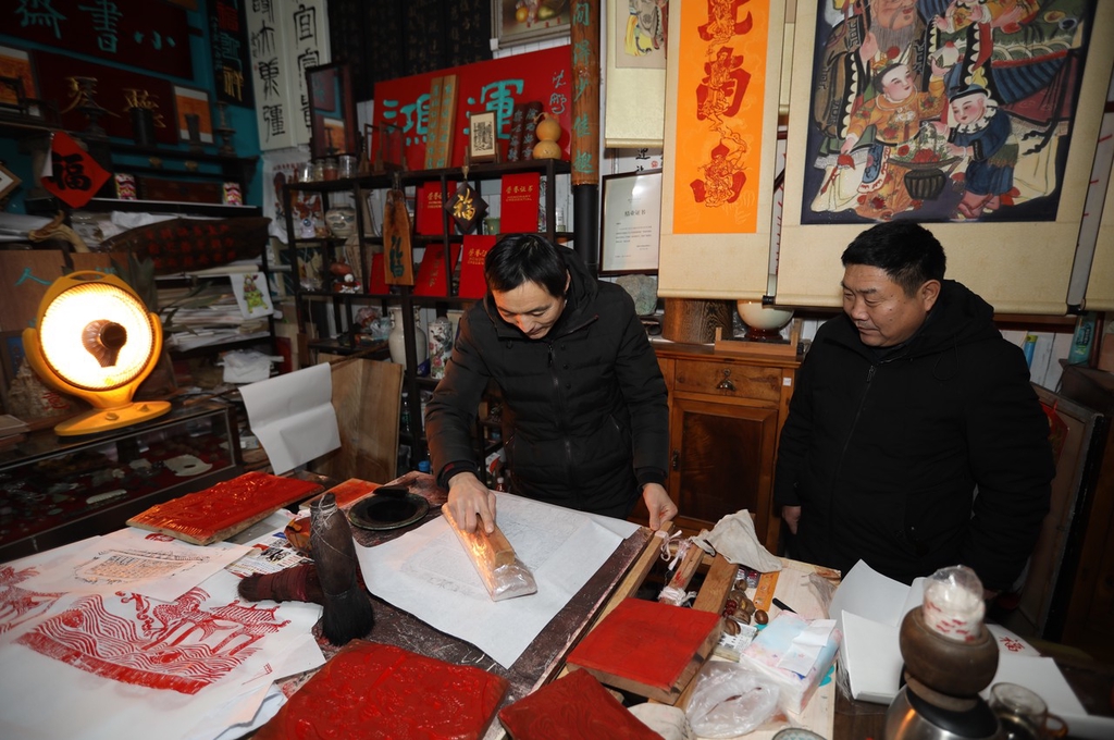 A photo shows craftsman Li Xiangduo imprinting an image onto a page in Rizhao, Shandong on December 20, 2023. /IC