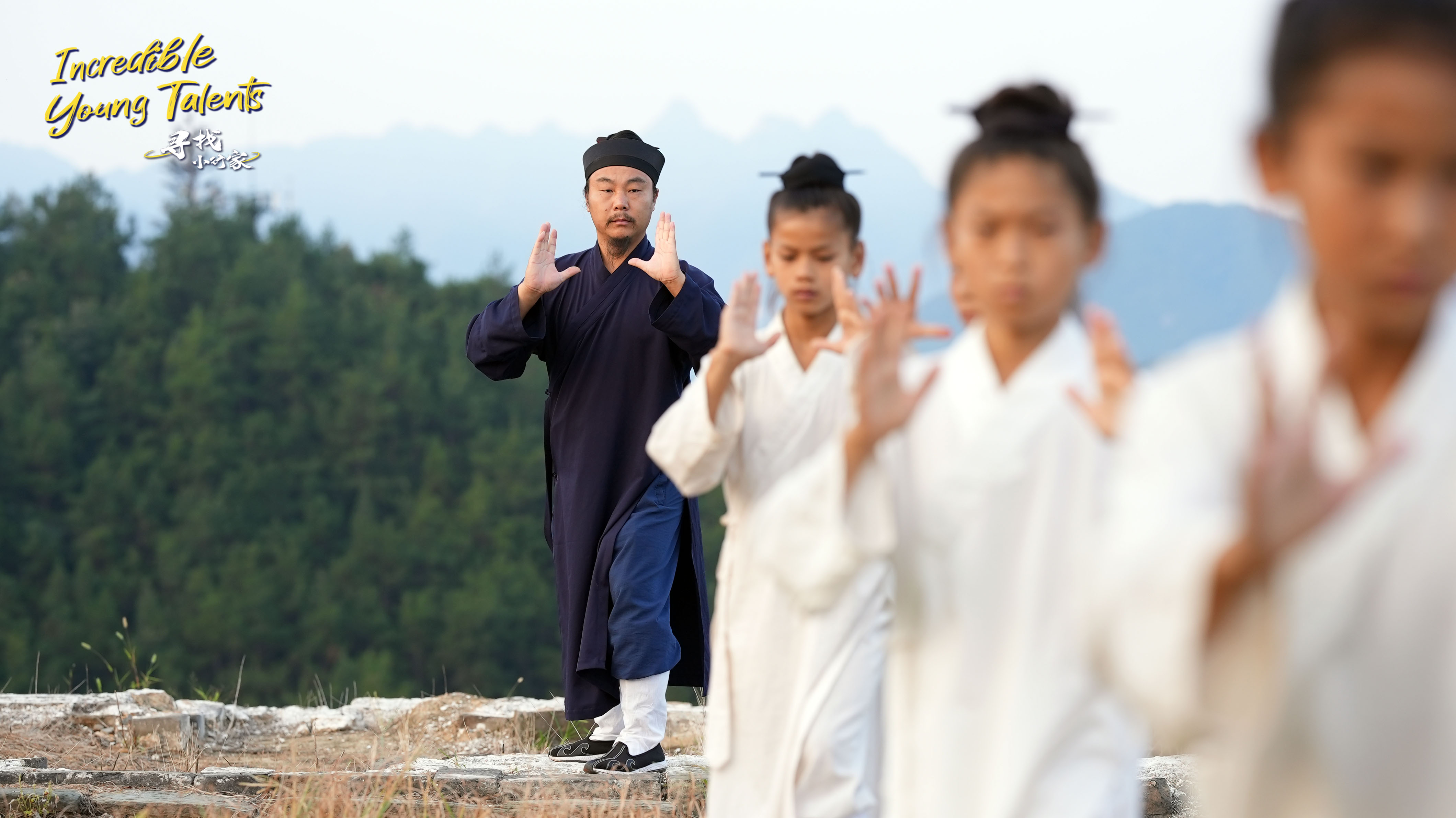 Tai Chi master Hu Weizhe (left) teaches young apprentices basic Tai Chi routines in the Wudang Mountains. /CGTN