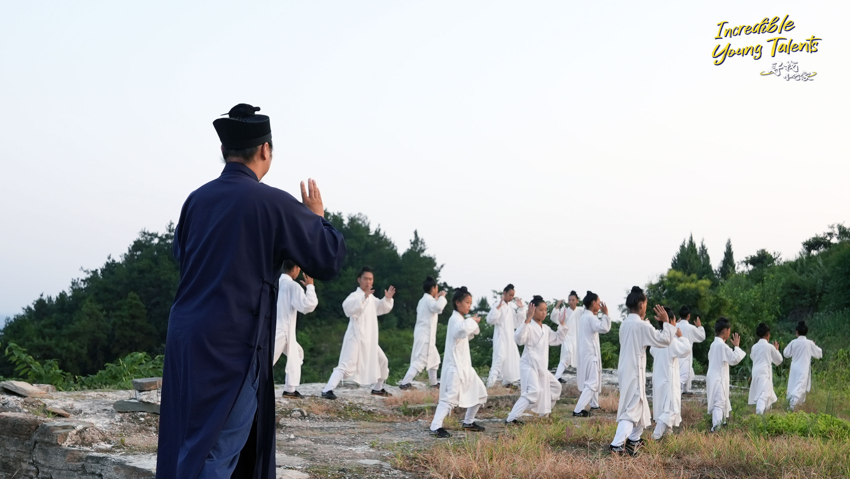 Tai Chi master Hu Weizhe (left) teaches young apprentices basic routines in the Wudang Mountains. /CGTN