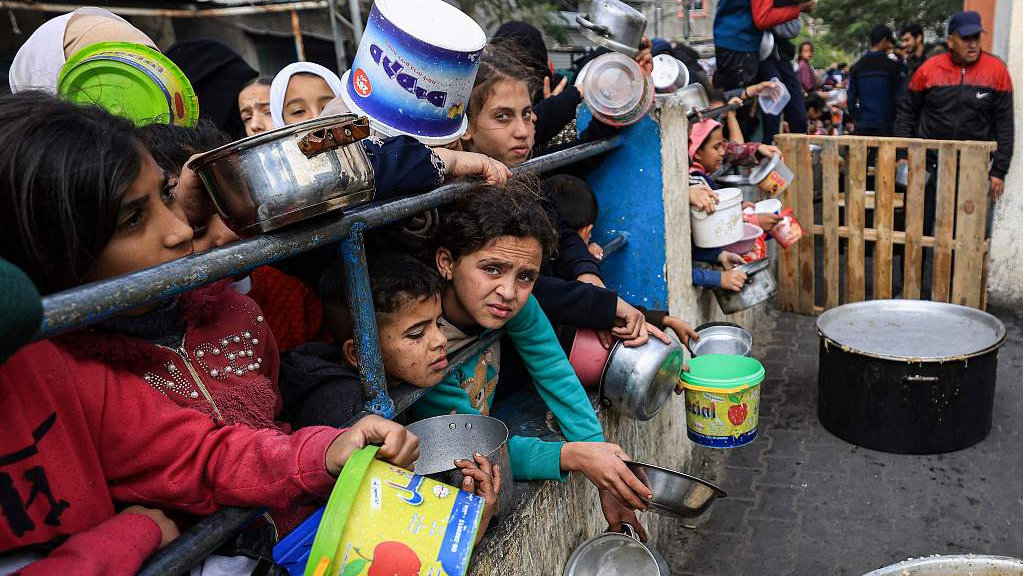 Palestinian children wait to collect food at a donation point in a refugee camp in Rafah in the southern Gaza Strip, December 23, 2023. /CFP