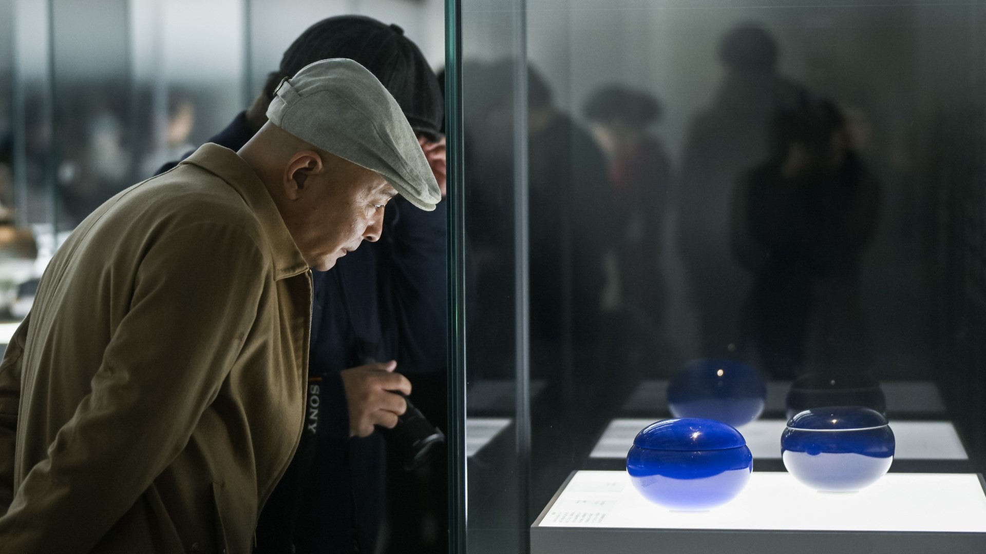 Visitors admire glassware on display at the Guardian Art Center in Beijing, December 22, 2023. /Photo provided to CGTN
