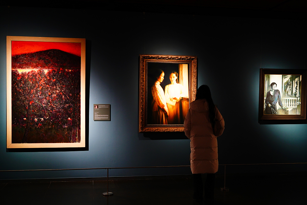 A photo taken on December 26, 2023 shows a visitor appreciating oil paintings on display at the National Centre for the Performing Arts in Beijing, China. /CFP