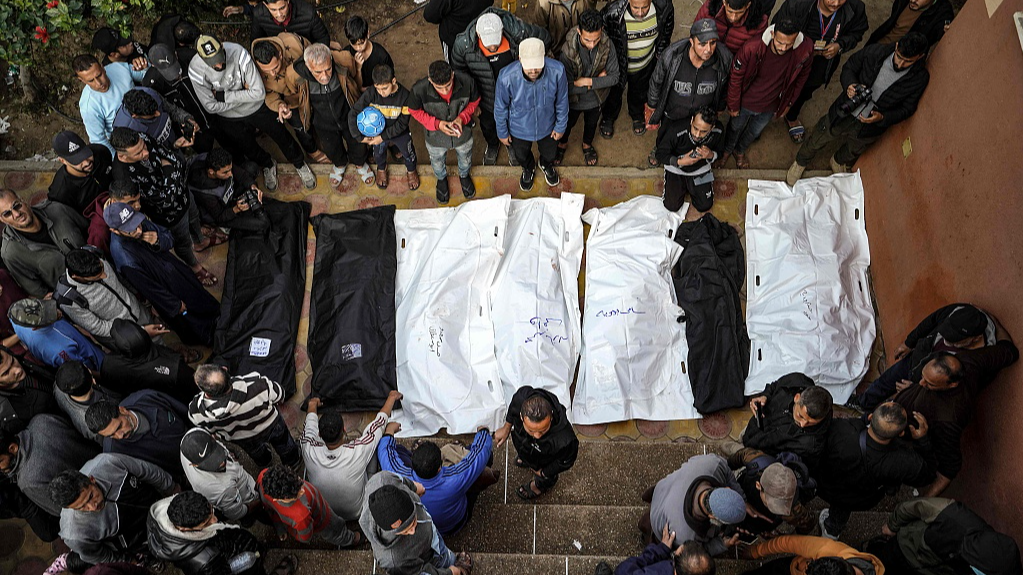 People stand over the shrouded bodies of loved ones killed during Israeli bombardment at Nasser Hospital in Khan Yunis in the southern Gaza Strip, December 27, 2023. /CFP