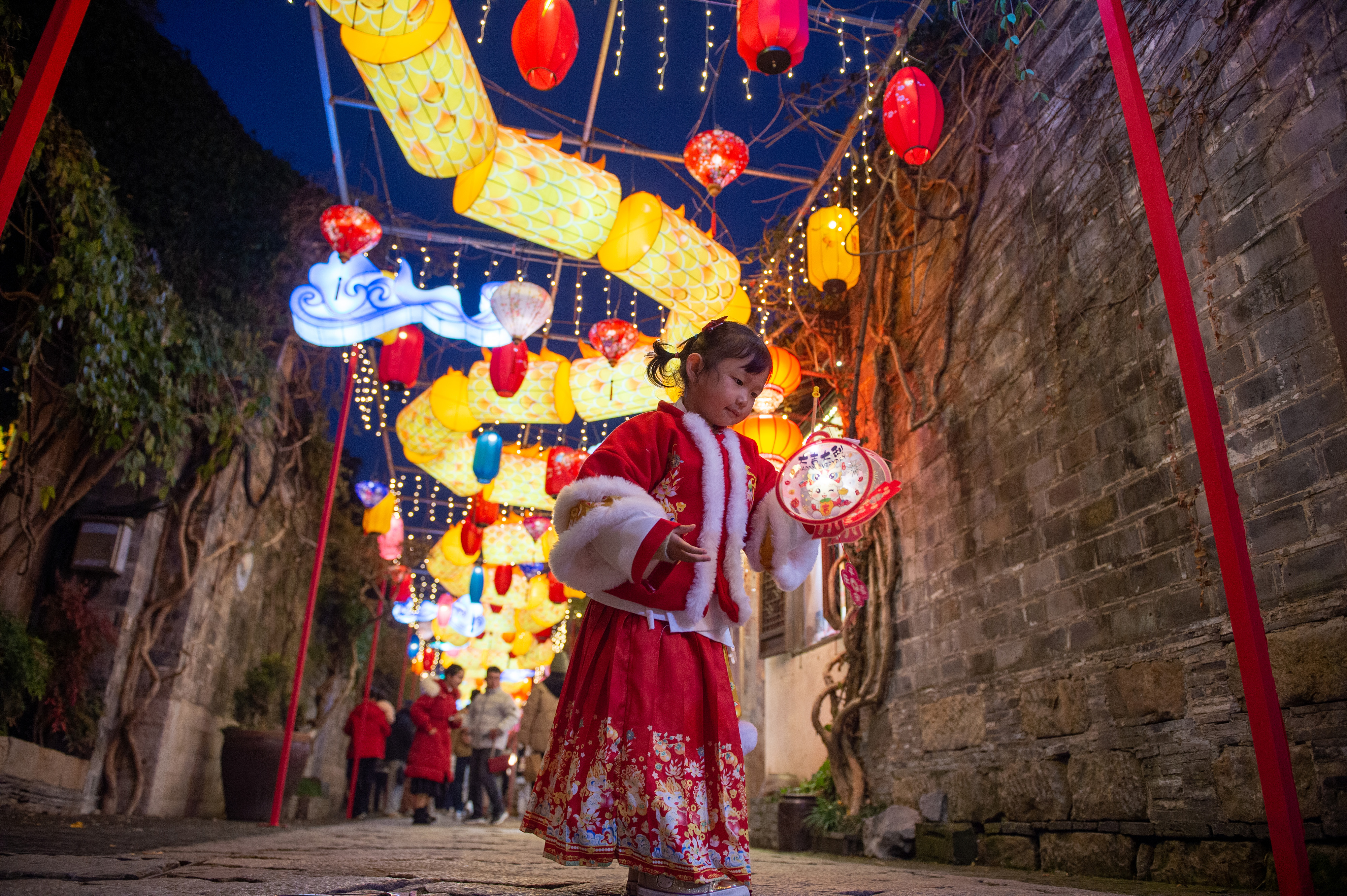 A girl holding a lantern is pictured at the Laomendong historic district of Nanjing in east China's Jiangsu Province on December 27, 2023./IC