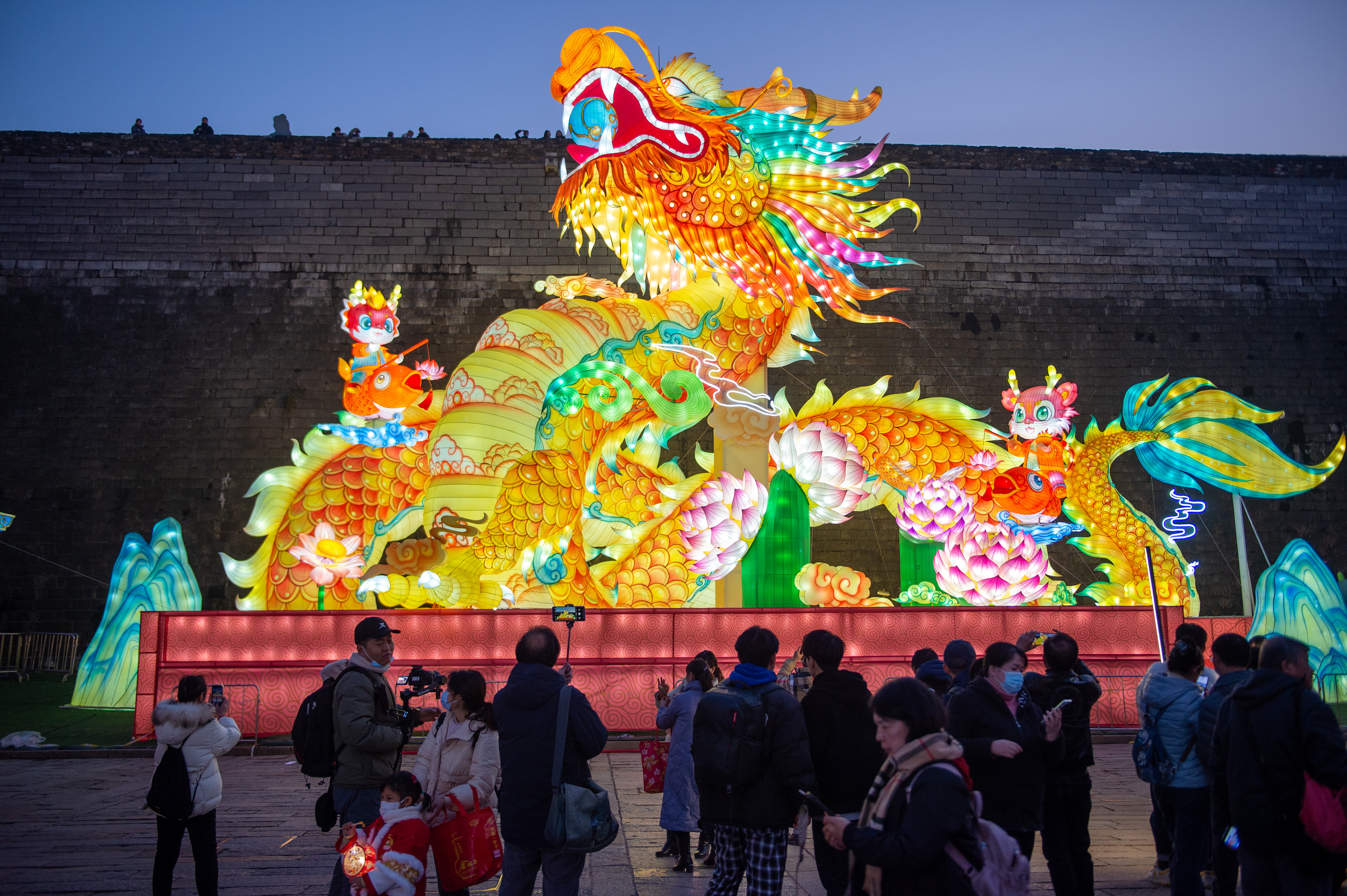 Visitors take photos of a giant dragon lantern at the Laomendong historic district of Nanjing in east China's Jiangsu Province on December 27, 2023. Festive lanterns have been installed in the area ahead of the upcoming Chinese New Year and Spring Festival celebrations. /IC