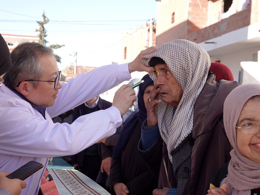 Hu Changrong (left), a member of the Chinese medical team to Tunisia, inspects the eyes of an old man during a free clinical activity in Tunisia's northwestern province of El Kef, on February 19, 2023. Photo: Xinhua.