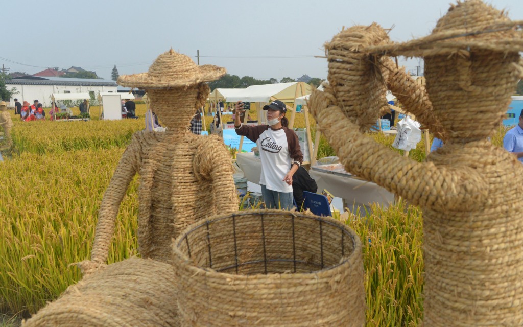 Visitor takes photos of artistic sculptures during a three-day music festival held in a paddy field in Changda Village, Shanghai on October 27, 2023. /CFP